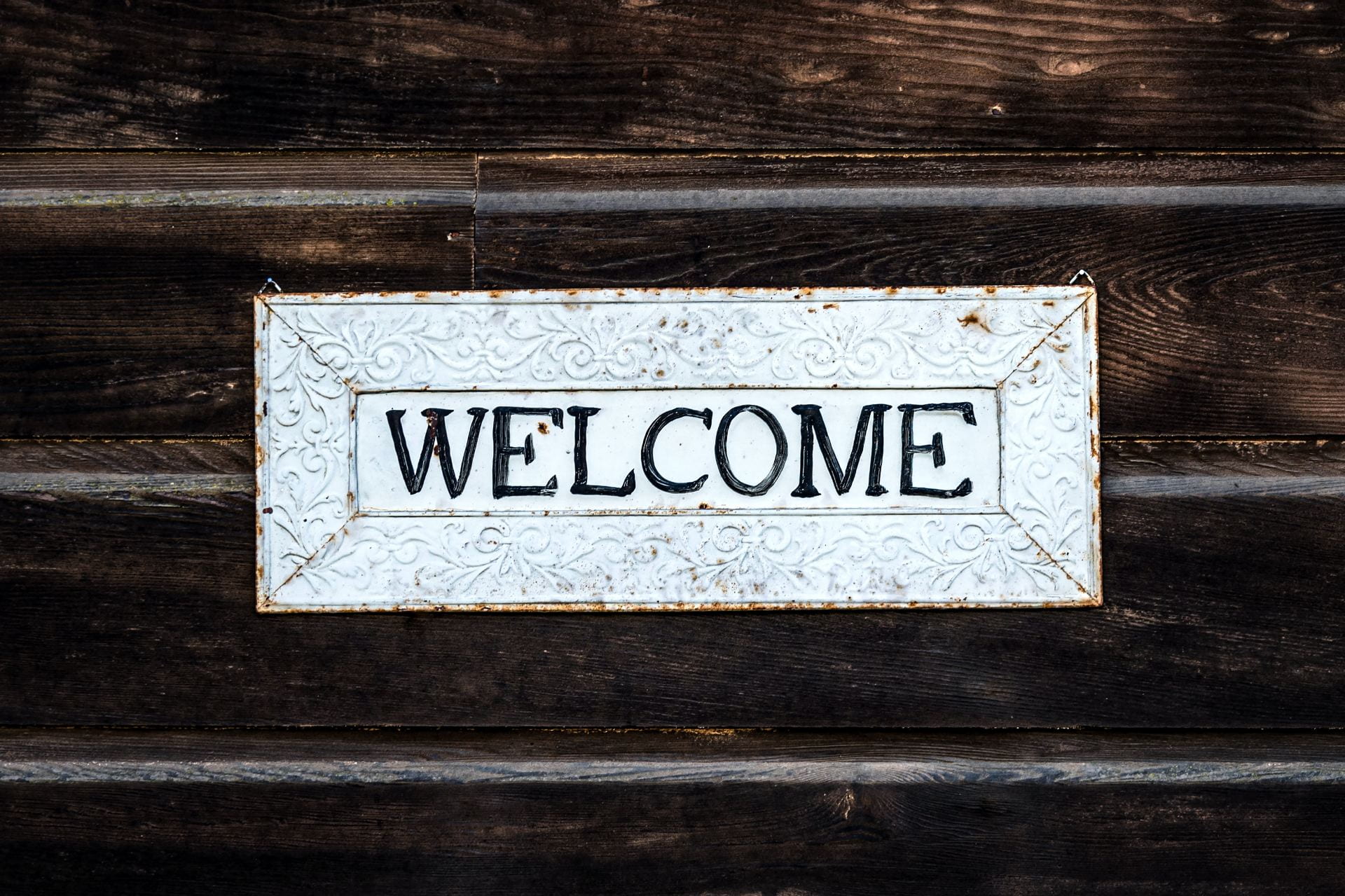 A welcome sign rests against a wooden background.